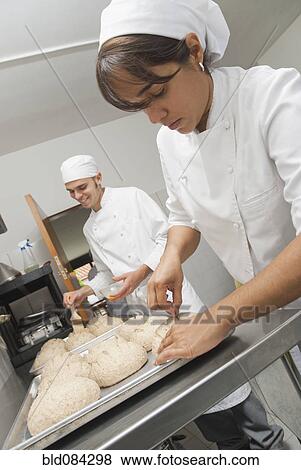 Bakers working with dough in bakery kitchen View Large Photo Image Stock Photo - Bakers working with dough in bakery kitchen. Fotosearch
