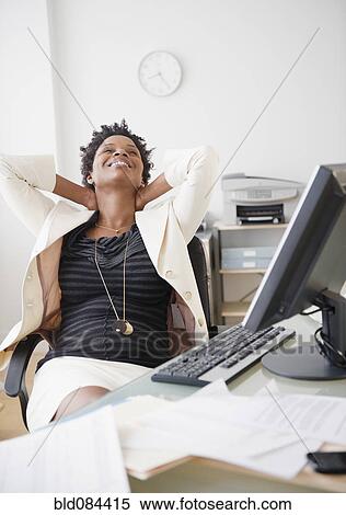 Stock Photography - Black businesswoman reclining at desk. Fotosearch