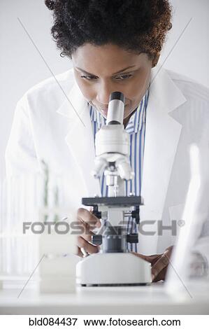 Stock Photo - Black scientist looking into microscope. Fotosearch