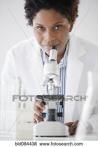 Black scientist standing with microscope View Large Photo Image Stock Photo - Black scientist standing with microscope. Fotosearch