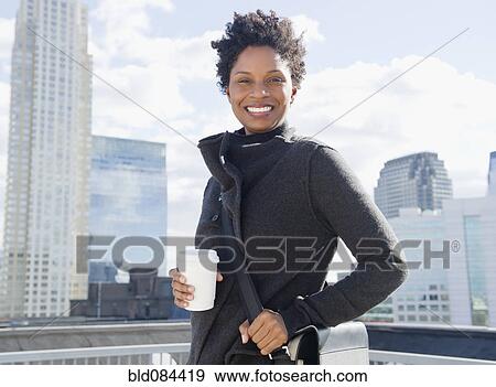 Stock Photo - Black woman drinking coffee on rooftop. Fotosearch