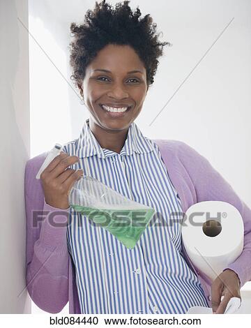 Stock Image - Black woman holding paper towels and spray bottle. Fotosearch