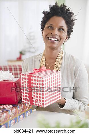 Stock Image - Black woman holding wrapped gift. Fotosearch
