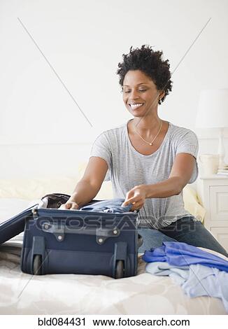 Stock Image - Black woman packing suitcase. Fotosearch