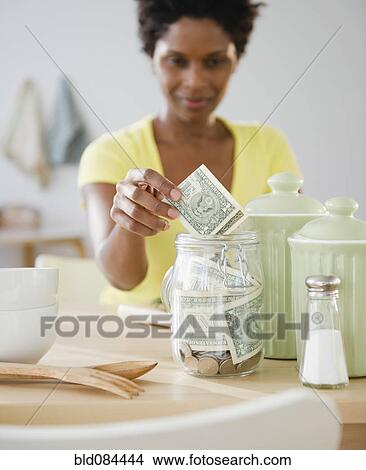 Black woman putting money in jar View Large Photo Image Picture - Black woman putting money in jar. Fotosearch