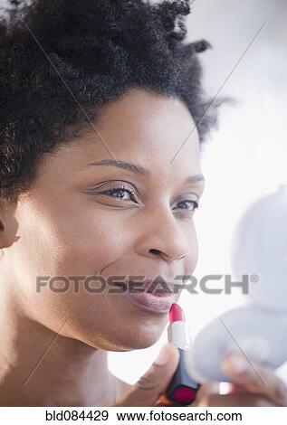 Stock Photo - Black woman putting on lipstick. Fotosearch