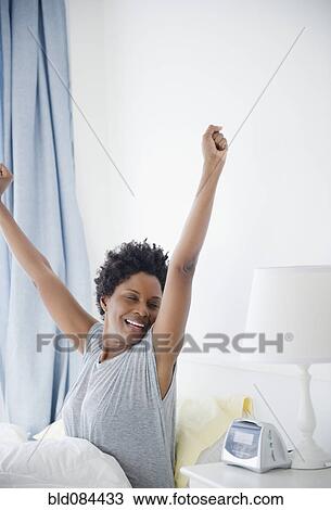Stock Image - Black woman waking up in the morning. Fotosearch