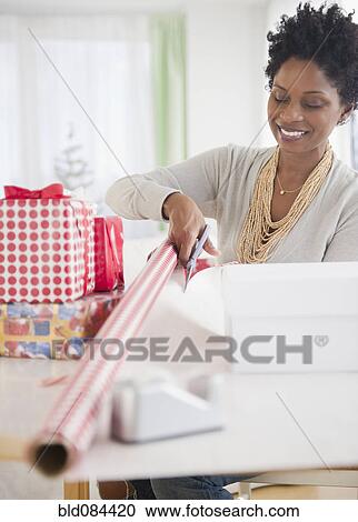 Stock Image - Black woman wrapping gifts. Fotosearch