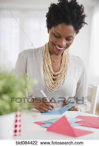 Stock Image - Black woman writing on birthday card. Fotosearch