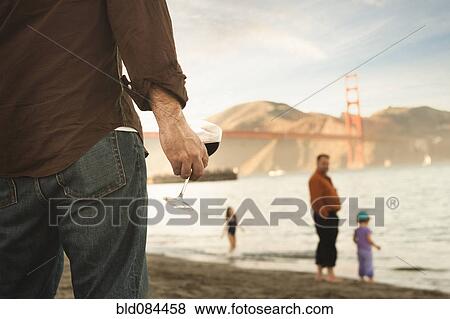 Stock Photo - Caucasian man drinking wine on beach. Fotosearch