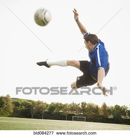 Caucasian soccer player in mid-air kicking soccer ball View Large Photo Image Stock Photo - Caucasian soccer player in mid-air kicking soccer ball. Fotosearch