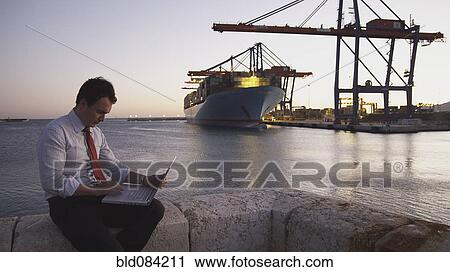 Hispanic businessman with laptop with container ship in background View Large Photo Image Stock Image - Hispanic businessman with laptop with container ship in background. Fotosearch