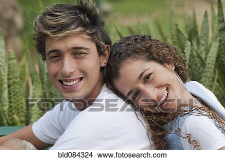 Picture - Hispanic couple sitting back to back. Fotosearch