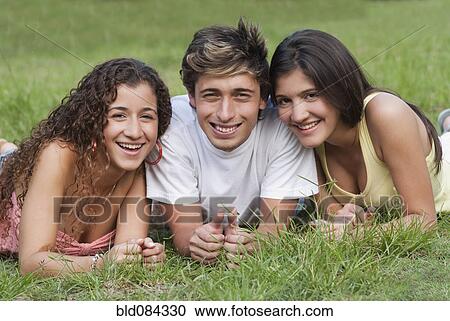 Stock Image - Hispanic friends laying in grass together. Fotosearch