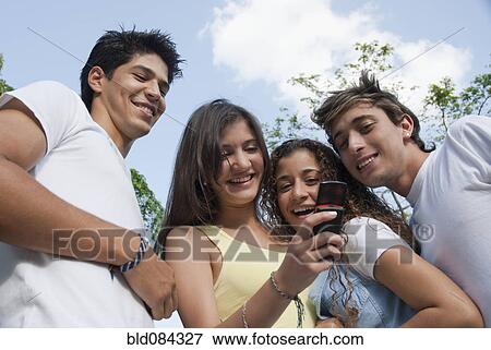 Hispanic friends looking at cell phone together View Large Photo Image Stock Photo - Hispanic friends looking at cell phone together. Fotosearch
