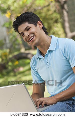 Hispanic man using laptop outdoors View Large Photo Image Stock Image - Hispanic man using laptop outdoors. Fotosearch