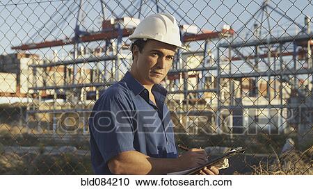 Stock Image - Hispanic man with clipboard on construction site. Fotosearch