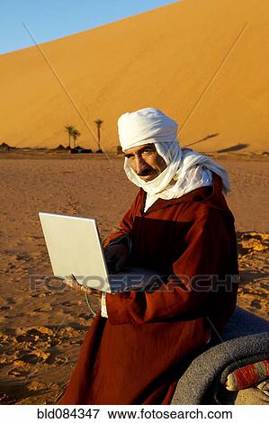 Stock Photo - Man using laptop in desert. Fotosearch