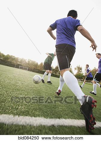 Stock Image - Men playing soccer on soccer field. Fotosearch