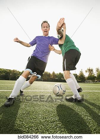 Stock Photograph - Men playing soccer on soccer field. Fotosearch