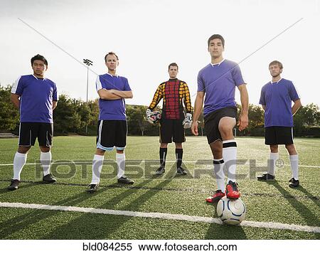 Stock Photography - Men standing with ball on soccer field. Fotosearch