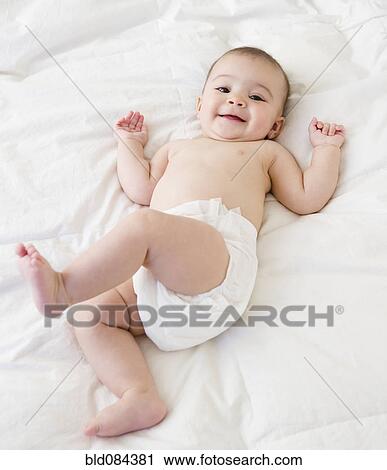 Stock Image - Mixed race baby laying on bed. Fotosearch