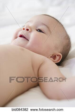 Stock Image - Mixed race baby laying on bed. Fotosearch