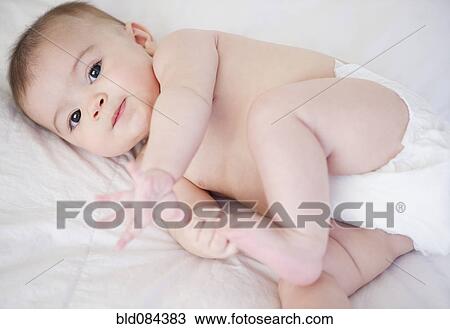 Stock Image - Mixed race baby laying on bed. Fotosearch