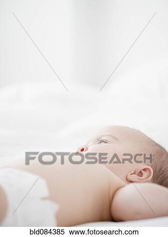 Stock Photography - Mixed race baby laying on bed. Fotosearch