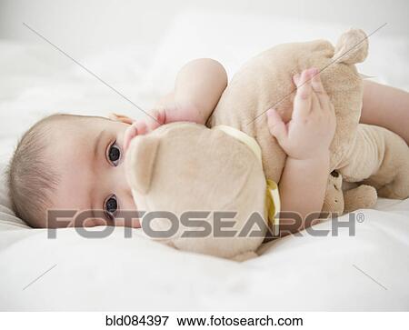 Mixed race baby laying on bed with teddy bear View Large Photo Image Stock Photo - Mixed race baby laying on bed with teddy bear. Fotosearch