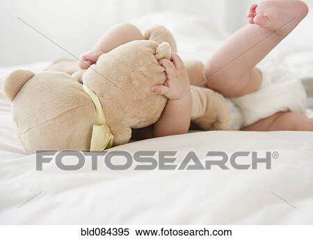 Mixed race baby laying on bed with teddy bear View Large Photo Image Stock Photography - Mixed race baby laying on bed with teddy bear. Fotosearch