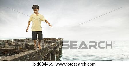 Stock Photography - Mixed race boy walking on dilapidated pier. Fotosearch