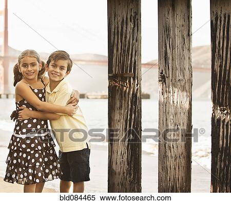 Stock Photography - Mixed race brother and sister hugging on beach. Fotosearch