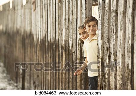 Stock Image - Mixed race brother and sister playing near wall. Fotosearch