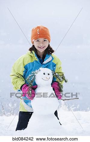 Mixed race girl building snowman View Large Photo Image Stock Image - Mixed race girl building snowman. Fotosearch