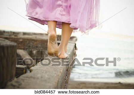 Stock Photo - Mixed race girl in costume walking on dilapidated pier. Fotosearch