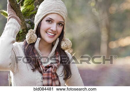 Stock Image - Mixed race woman in cap standing outdoors. Fotosearch