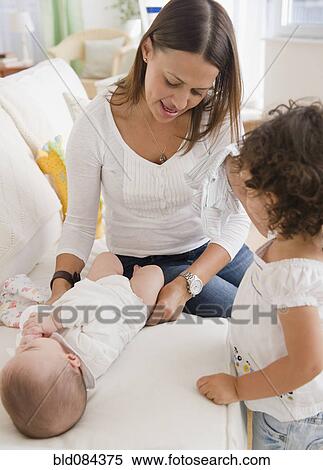 Mother changing baby's diaper on sofa View Large Photo Image Stock Photography - Mother changing baby's diaper on sofa. Fotosearch