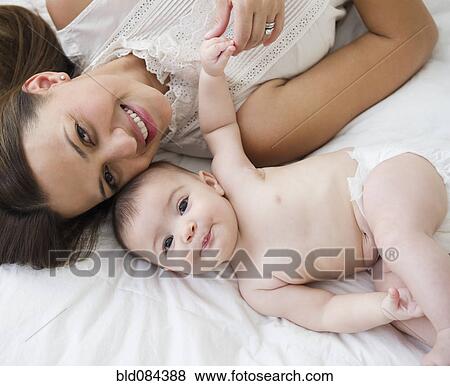 Stock Photo - Mother laying on bed with baby. Fotosearch