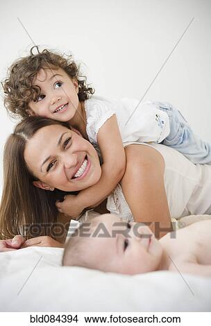 Picture - Mother playing on bed with daughters. Fotosearch
