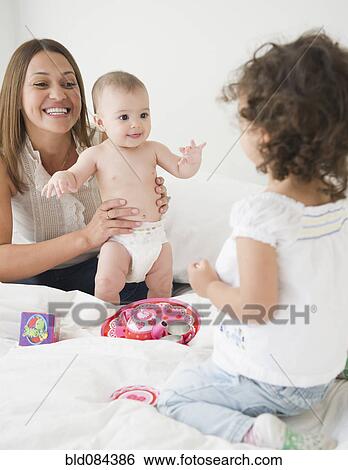Mother sitting on bed with daughters View Large Photo Image Stock Photograph - Mother sitting on bed with daughters. Fotosearch