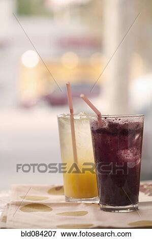 Stock Photo - Orange and grape juice in glasses with straws. Fotosearch