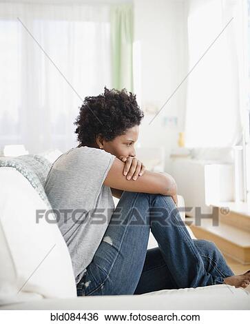 Serious Black woman sitting on sofa View Large Photo Image Stock Photograph - Serious Black woman sitting on sofa. Fotosearch