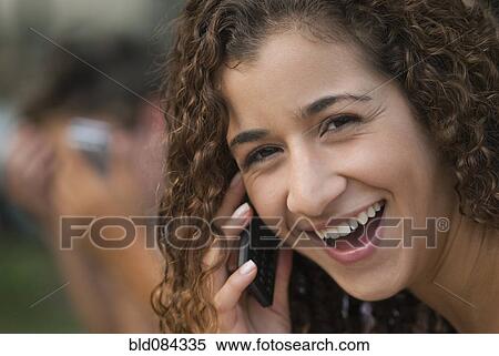 Stock Photography - Smiling Hispanic woman talking on cell phone. Fotosearch