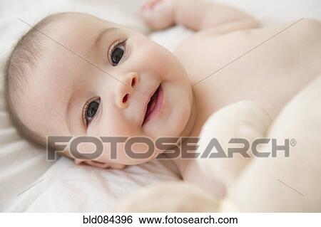 Stock Photograph - Smiling mixed race baby laying on bed. Fotosearch