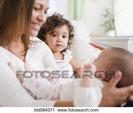 Stock Image - Smiling mother sitting with daughters. Fotosearch