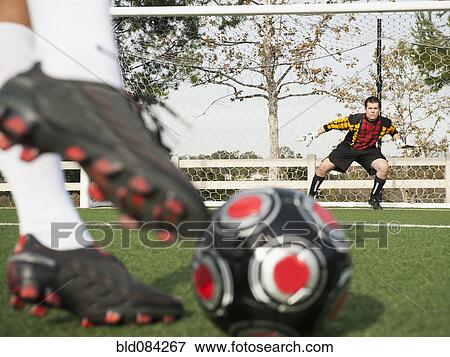 Stock Photo - Soccer player kicking ball into goal on soccer field. Fotosearch