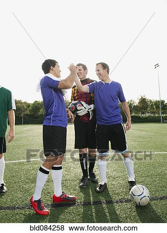 Stock Photo - Soccer players cheering on soccer field. Fotosearch