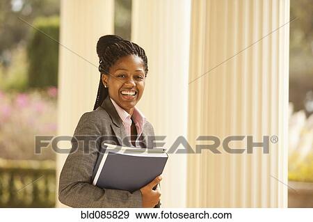 Stock Photo - African American businesswoman holding paperwork outdoors. Fotosearch