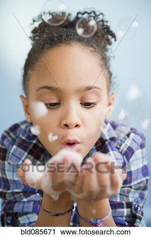 Stock Image - African American girl blowing bubbles. Fotosearch